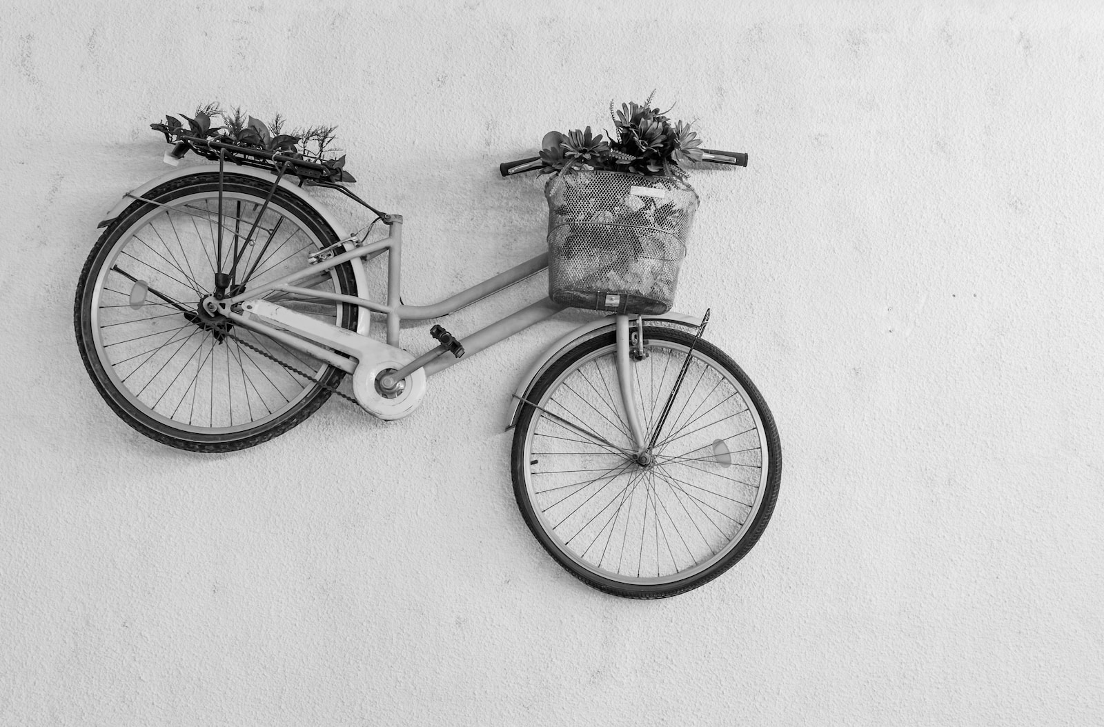 black bicycle with basket on white wall