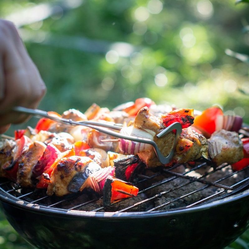 person holding fork and knife slicing meat on black grill